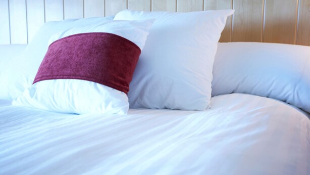 A bed with white bedding and a single red pillow. - Inn At The Park (Aberdeen)