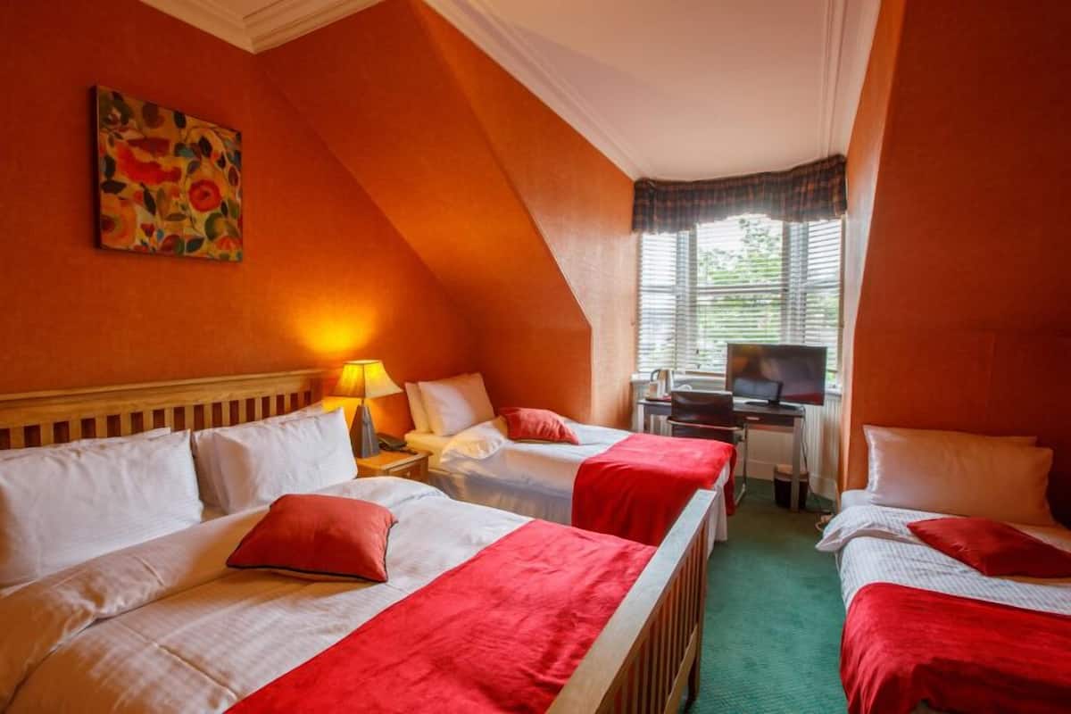 A hotel room with two beds, a desk with a computer, and a painting on the wall.