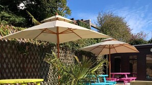 A patio area with outdoor seating, including yellow and blue benches, and two large umbrellas providing shade. - Inn At The Park (Aberdeen)