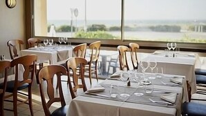 A restaurant with tables set for dining, chairs, and a view of the sea. - Le Calluna (Prefailles)