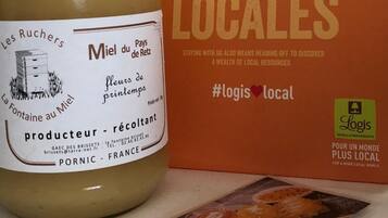 Un tarro de miel con la etiqueta 'Les Ruchers' y un folleto con el título 'Miel du Pays de Retz' y el hashtag '#logis local'.