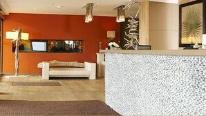 A modern lobby with a reception desk, a white sofa, and a large abstract art piece on the wall. - Le Calluna (Prefailles)