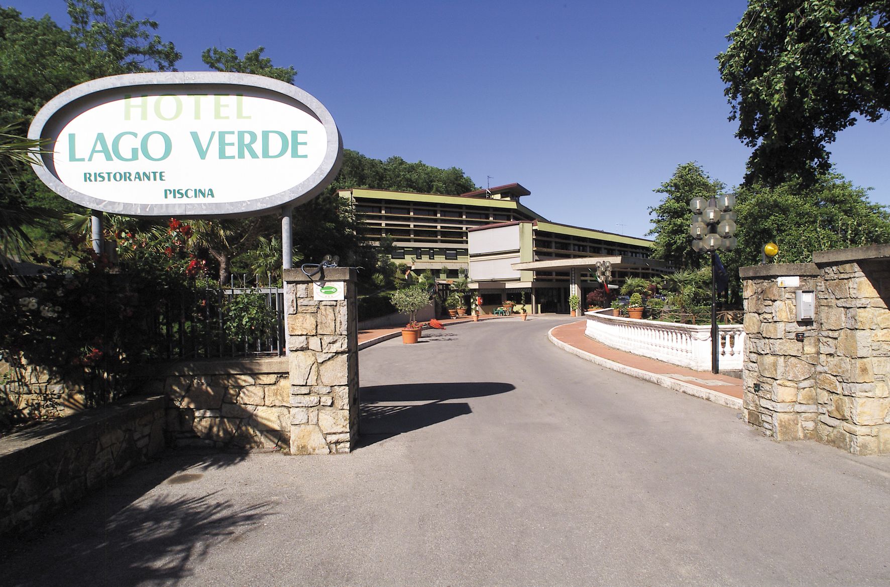 Entrada de un hotel con un letrero que dice "Hotel Lago Verde Restaurante Piscina".