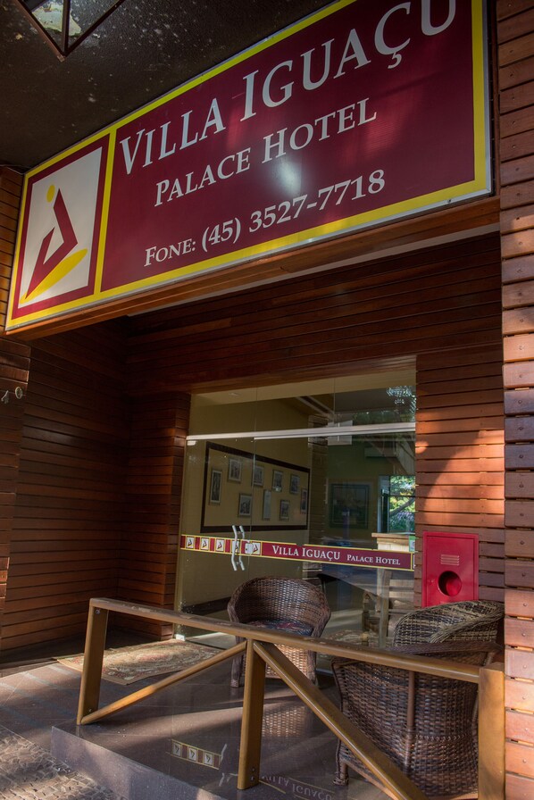 The exterior of Villa Iguacu Palace Hotel with a prominent signboard displaying the hotel's name and contact number.