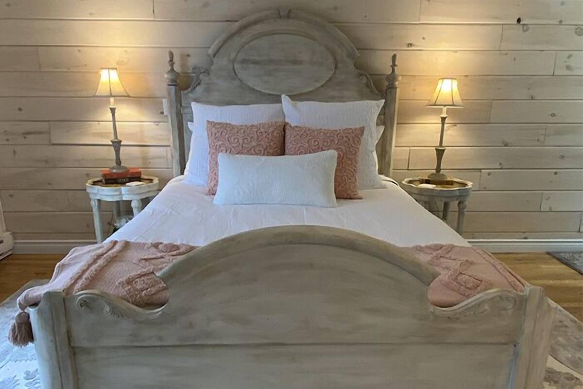 A bed with a wooden headboard, two bedside tables with lamps, and a white bedspread.