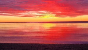 Atardecer sobre un cuerpo de agua tranquilo con un horizonte despejado.