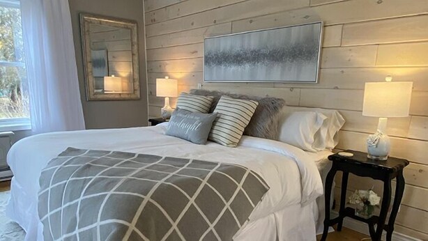 Un dormitorio con una cama grande, dos mesitas de noche con lámparas, un espejo y un cuadro en la pared.