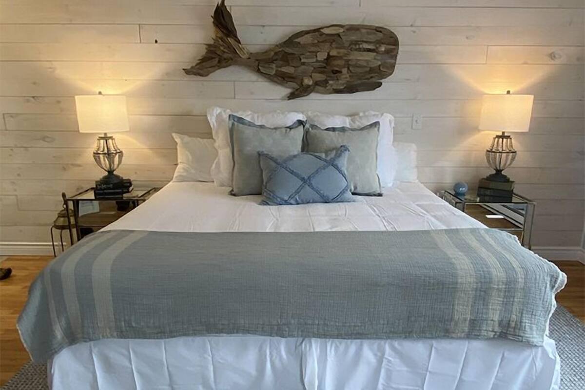 A bedroom with a bed, two nightstands, lamps, and a stone fish decoration on the wall.