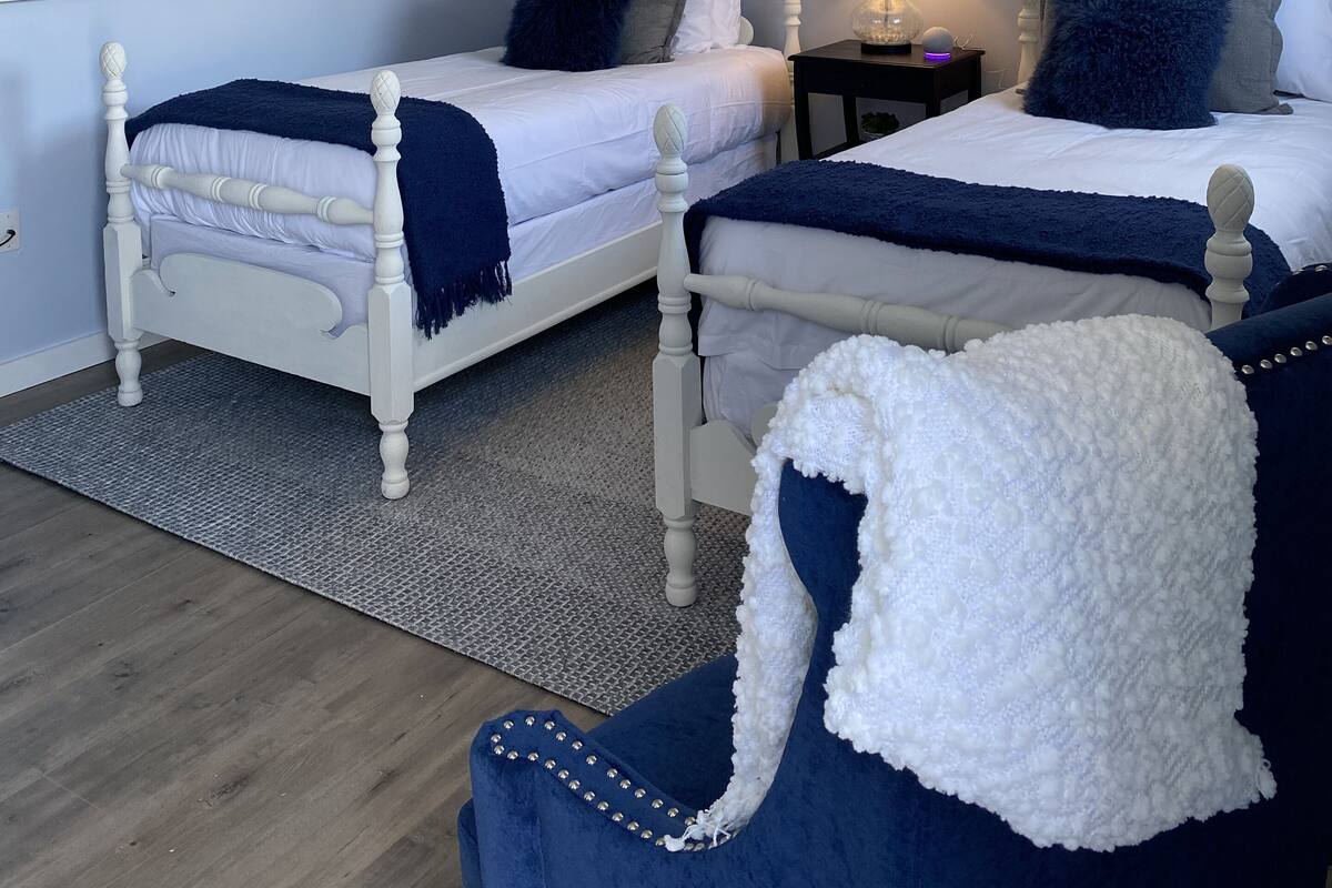 A bedroom with two beds, a nightstand, a lamp, and a painting on the wall.