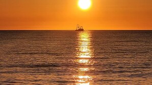 A boat on calm water with a sunset in the background.