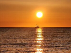 A boat on calm water with a sunset in the background.