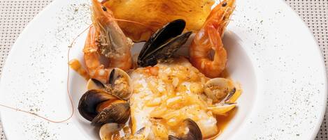 A seafood dish with mussels, clams, shrimp, and a piece of bread on a white plate.