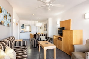 A modern living room with striped sofas, a wooden coffee table, and a TV cabinet. - Ona el Marqués Resort (Santiago del Teide)