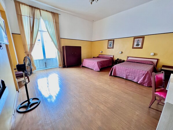A hotel room with two beds, a wardrobe, a fan, and a door leading to a balcony. - Hotel Isabel (Mexico City)