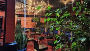 An indoor seating area with tables and chairs, potted plants, and string lights. - Hotel Isabel (Mexico City)