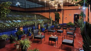 An indoor area with ceiling lights, potted plants, and seating arrangements. - Hotel Isabel (Mexico City)