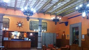 A lobby with a reception desk, wooden chairs, and a high ceiling with skylights. - Hotel Isabel (Mexico City)