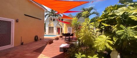 A courtyard with a tiled floor, outdoor seating, and a pool in the background.