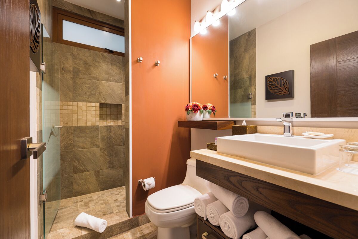 Ein Badezimmer mit Dusche, Toilette und Waschbecken, ausgestattet mit Spiegel, Handtuchhalter und Wanddekoration.