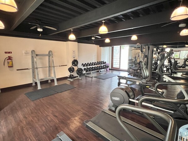 A gym with weightlifting equipment, treadmills, and dumbbells.