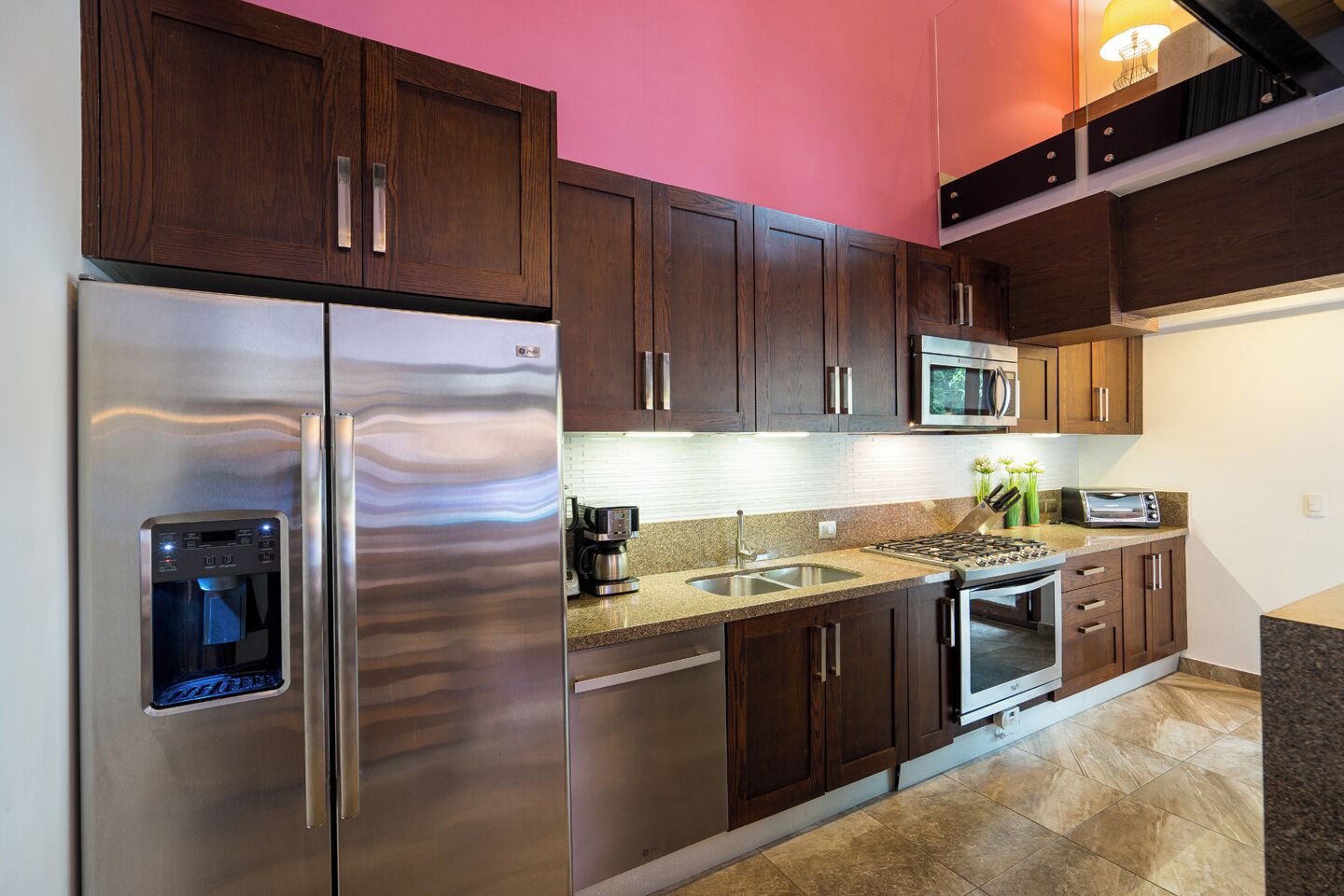 A modern kitchen with stainless steel appliances, a built-in water dispenser, and a granite countertop.