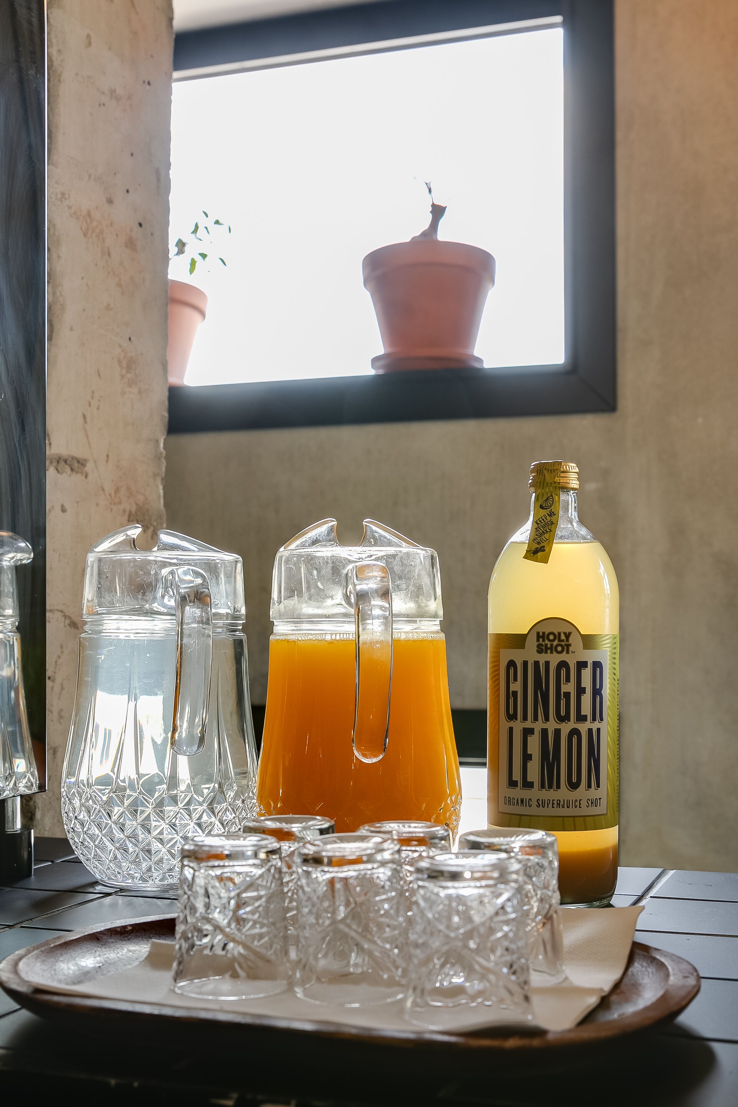 Ein Tisch mit einer Krug Zitronen-Ingwer-Saft, einem Glas Krug und mehreren Gläsern auf einer Serviertablett.