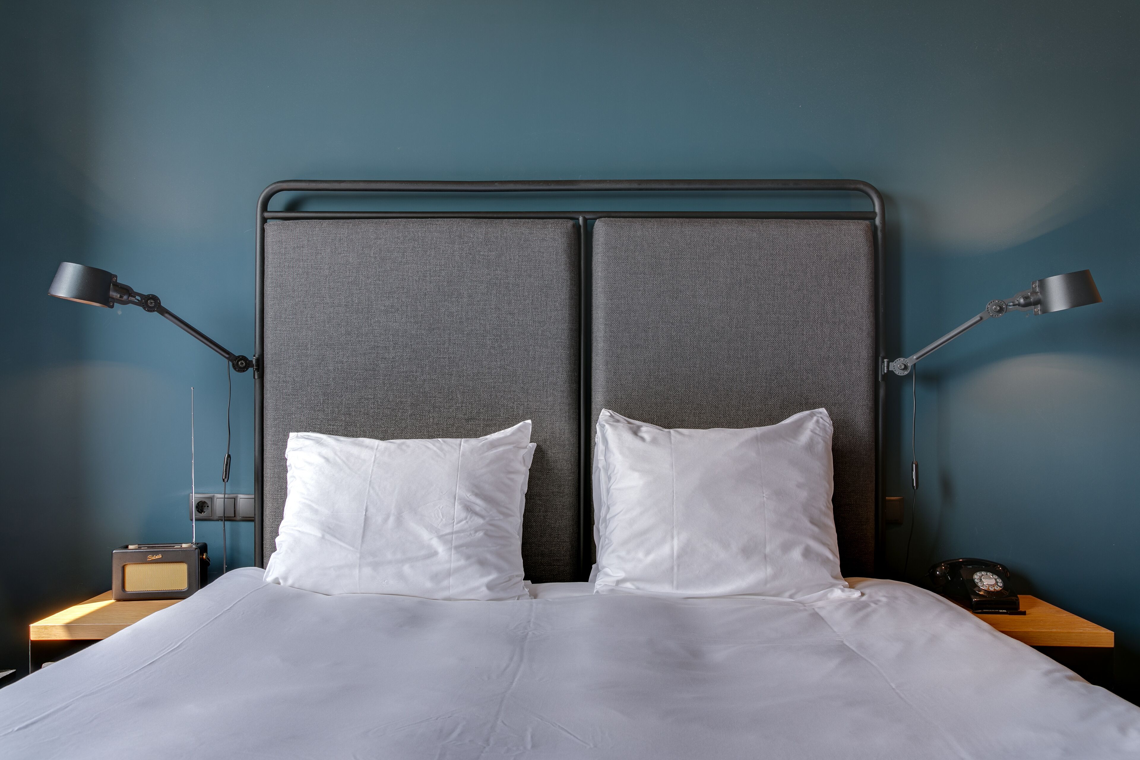 A bed with white bedding, two pillows, and two bedside lamps.