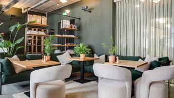 A modern interior with green sofas, wooden tables, and potted plants.