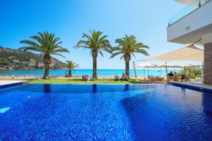 Una piscina al aire libre, sombrillas, sillones reclinables de piscina