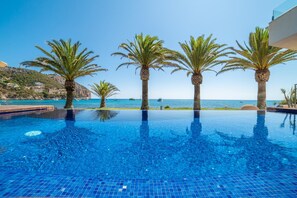 Una piscina al aire libre, sombrillas, sillones reclinables de piscina