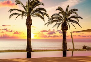 Una piscina al aire libre, sombrillas, sillones reclinables de piscina