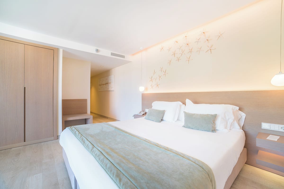 A modern hotel room with a large bed, a wooden wardrobe, and a wall-mounted starfish decoration.