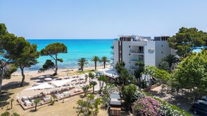 A coastal hotel with a beach view, outdoor seating, and a modern building. - Melbeach Hotel & Spa - Adults Only (Capdepera)