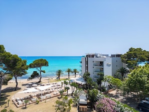 A coastal hotel with a pool area, outdoor seating, and a view of the sea.