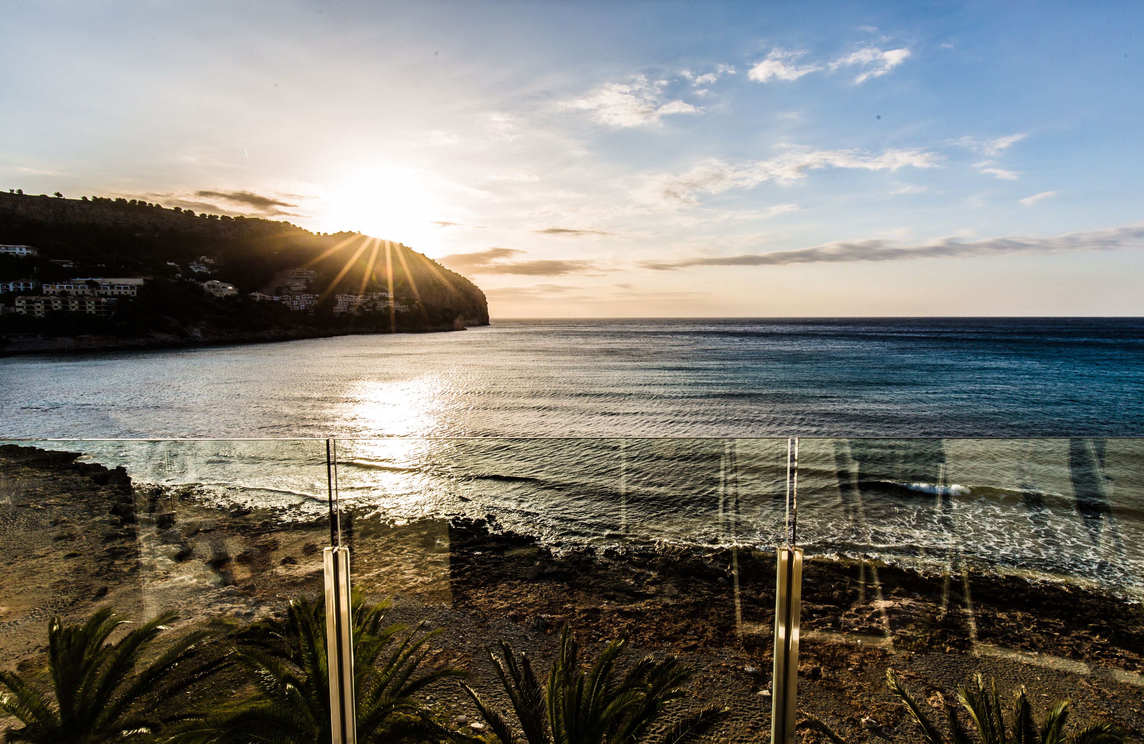 Un paysage côtier avec un ciel dégagé, une mer illuminée par le soleil et une côte rocheuse.