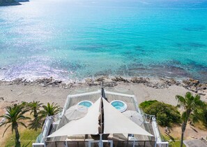 A beach view from a resort with a pool area, palm trees, and clear turquoise water. - Melbeach Hotel & Spa - Adults Only (Capdepera)