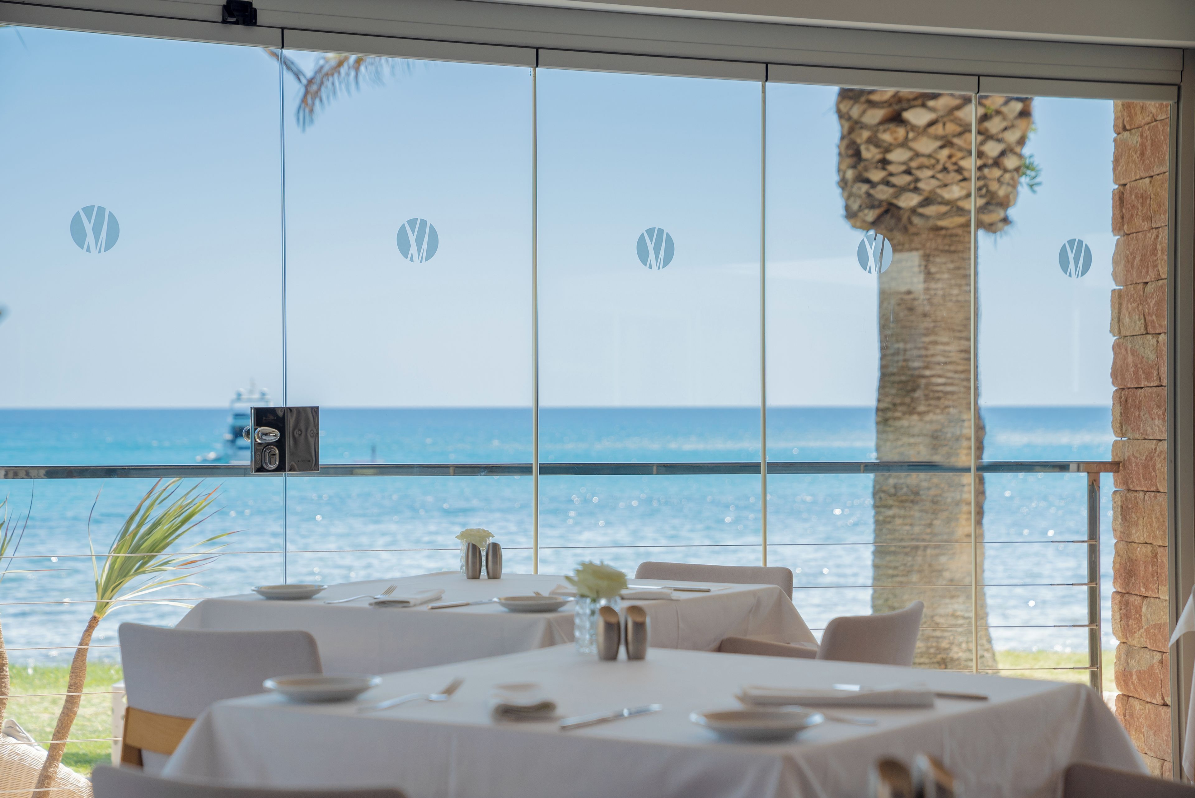 A restaurant with tables set for dining, overlooking a body of water.