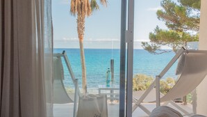A room with a view of the sea, a beach chair, a towel, and a table with a bottle. - Melbeach Hotel & Spa - Adults Only (Capdepera)