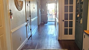 A hallway with a patterned rug, a ceiling light, and a door leading to another room. - Barclay Cottage (Virginia Beach)