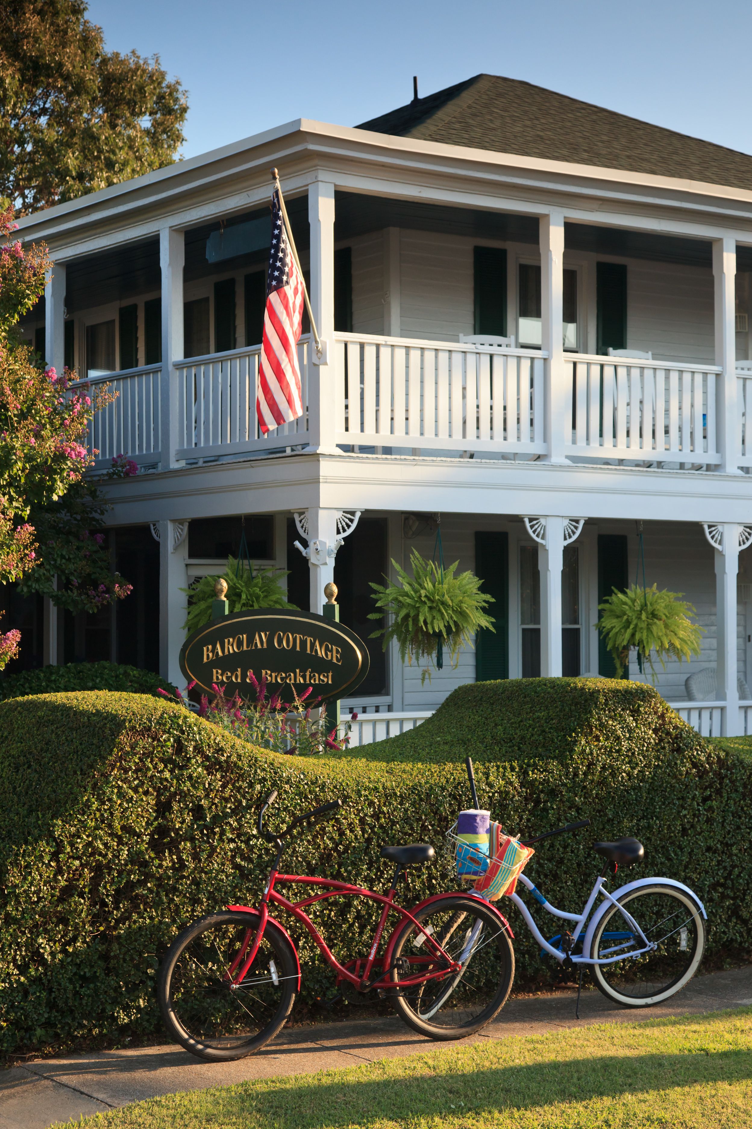 A two-story building with a porch, an American flag, and a sign that reads "Barclay Cottage Bed & Breakfast."