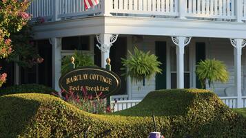 A two-story building with a porch, an American flag, and a sign that reads "Barclay Cottage Bed & Breakfast."
