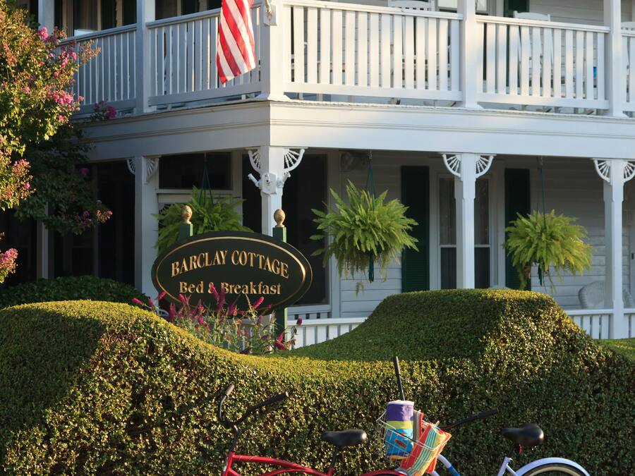 A two-story building with a porch, an American flag, and a sign that reads "Barclay Cottage Bed & Breakfast."