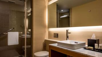 A modern bathroom with a glass shower enclosure, a white sink, and a large mirror.