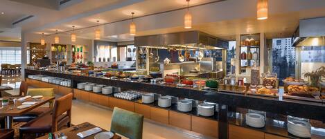 A modern hotel restaurant with a buffet setup, featuring a variety of food items and a well-lit dining area.