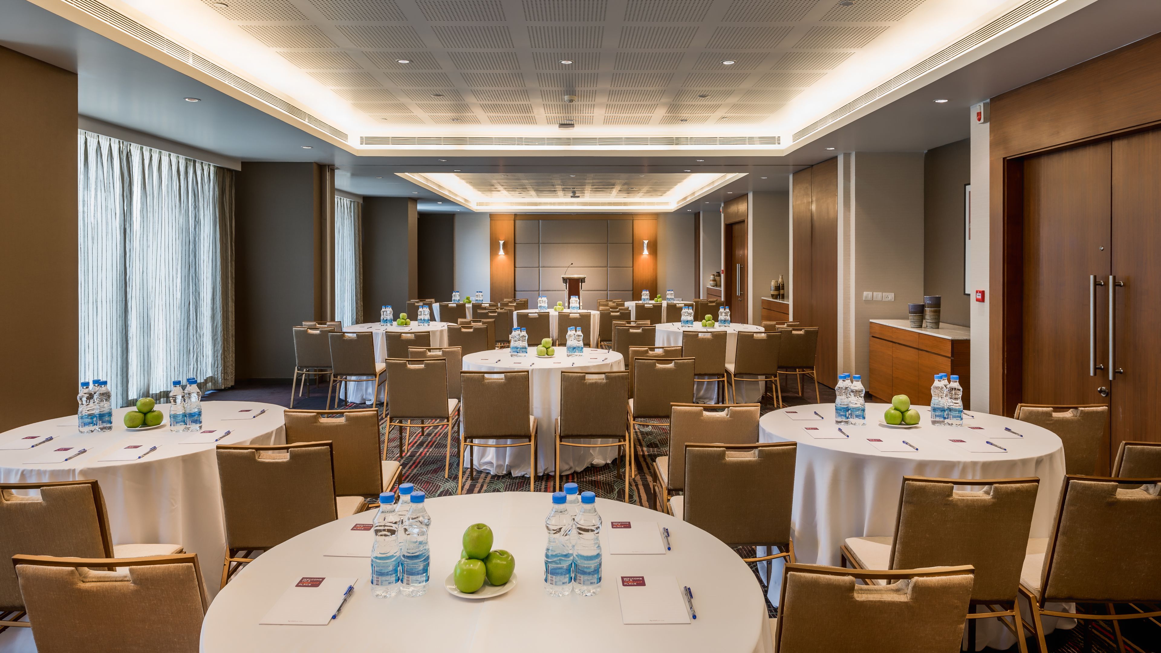 Un salón de conferencias con varias mesas, sillas y botellas de agua.