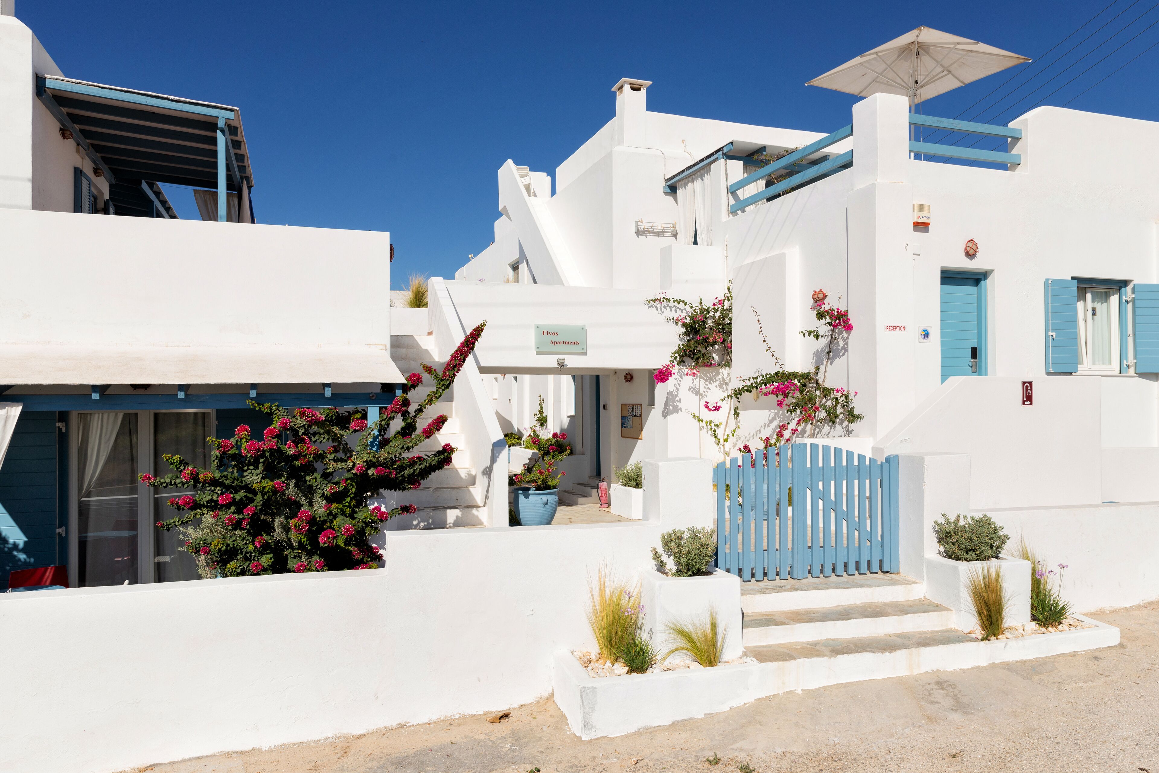 A white building with a blue door and steps leading to the entrance.
