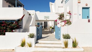A white building with a blue door and a sign reading "Evos Apartments". - Fivos Apartments (Paros)
