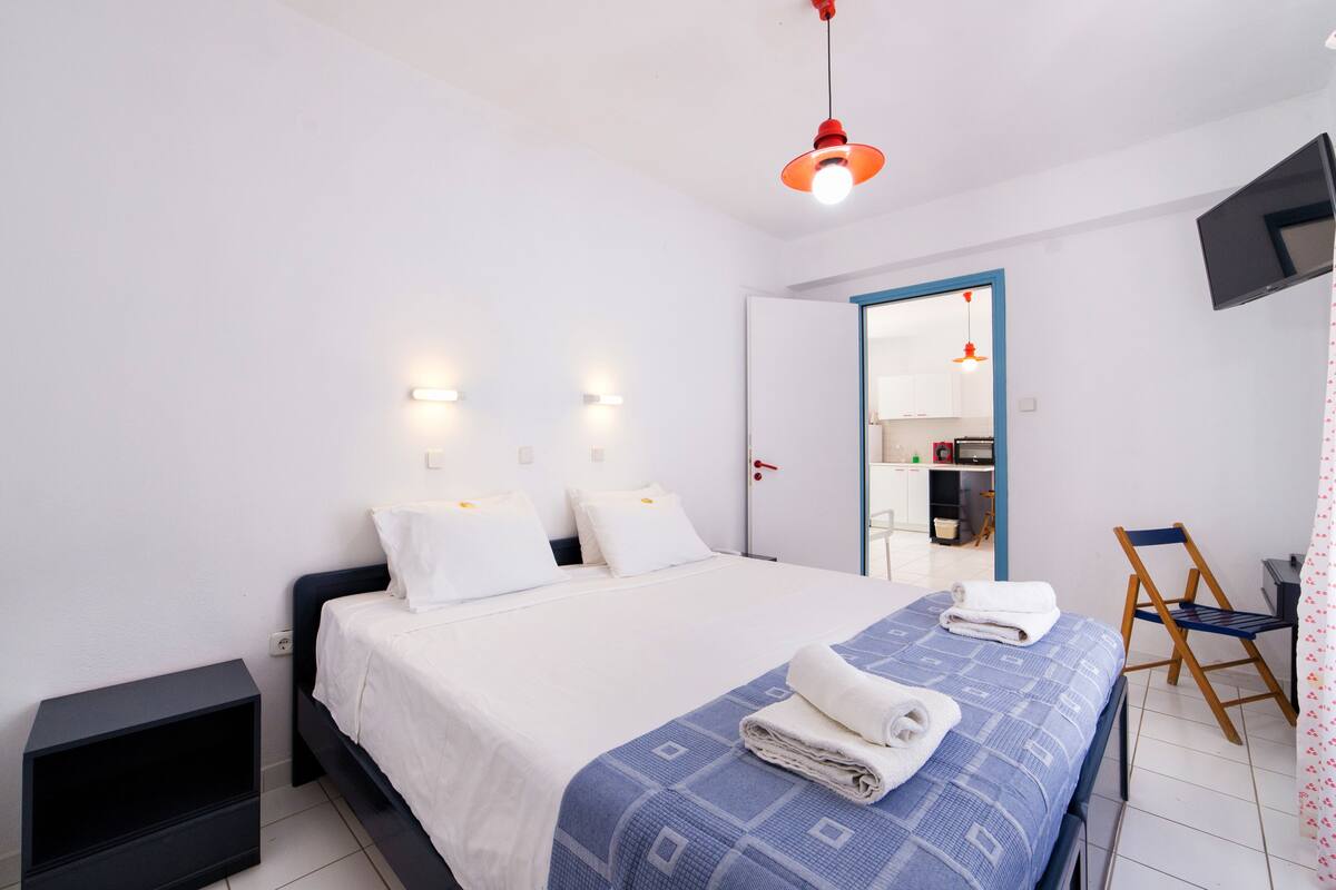 Una habitación de hotel moderna con una cama bien hecha, un televisor de pantalla plana montado en la pared y una pequeña zona de escritorio.