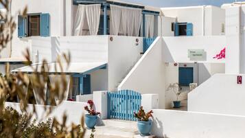 Un edificio blanco con contraventanas azules y un letrero que dice 'Fivos Apartments'.
