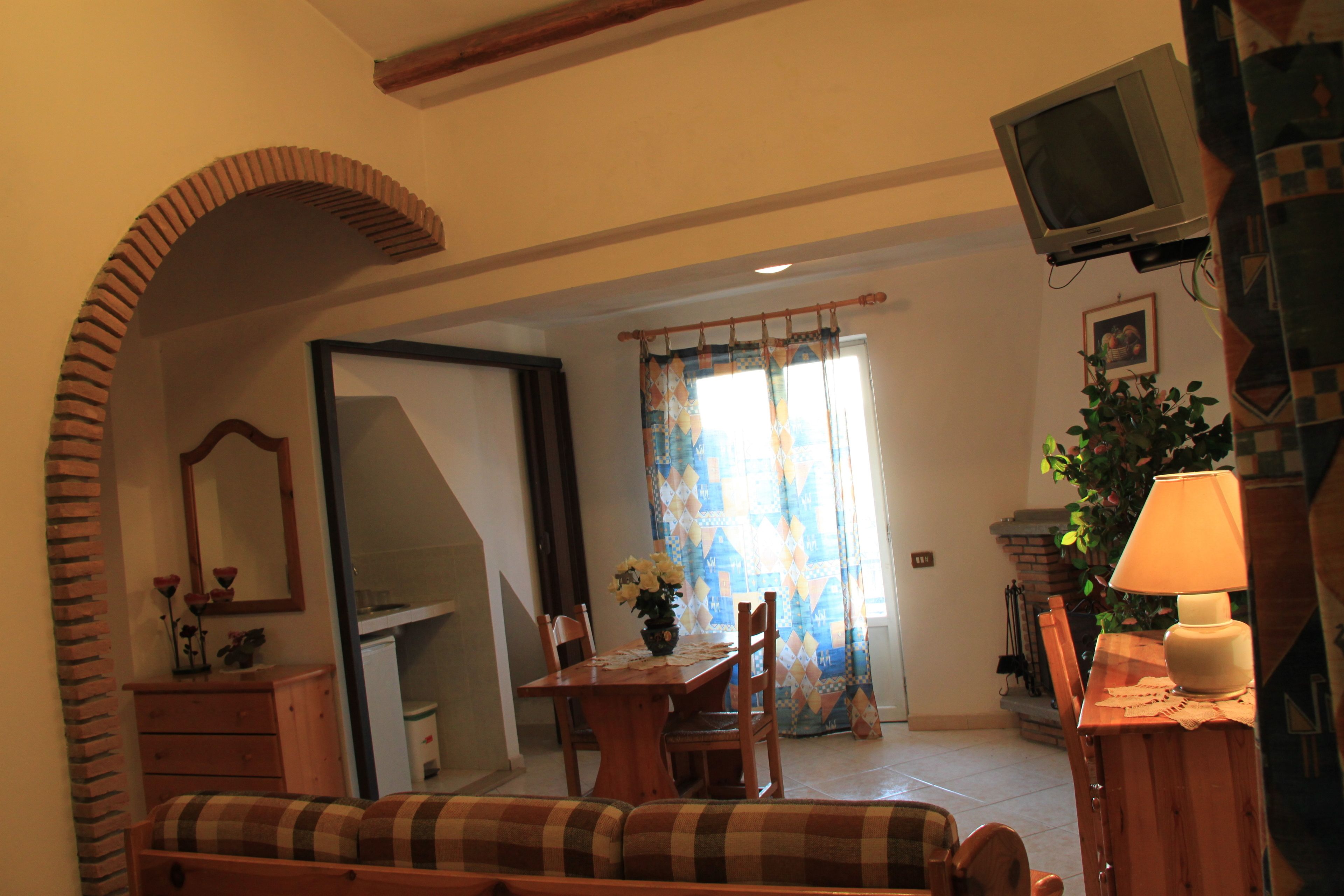 Un salón acogedor con una mesa de comedor de madera, un sofá y un televisor montado en la pared.
